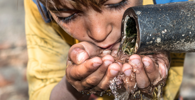 a boy drinking water from a tap
