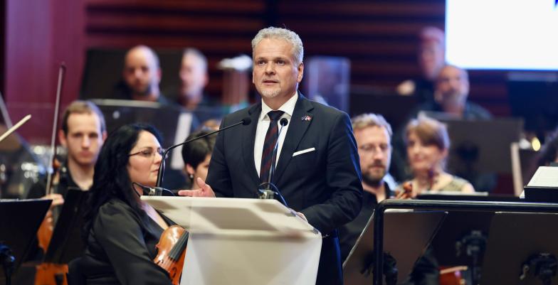 Ambassador Sattler standing behind lectern