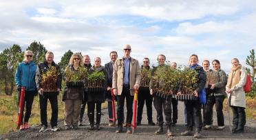 Picture of a large group of people, some holding small tree plants