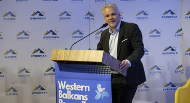 Ambassador Sattler standing behind lectern and speaking