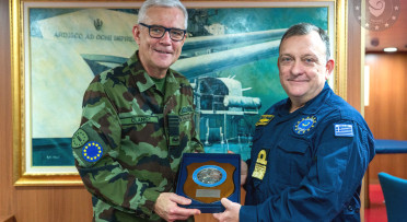 Two military men smile at the camera indoors while awarding a medal. 