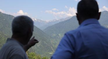 Two men watching mountains, one pointing in distance