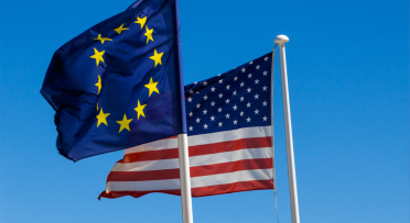 EU and US Flags flying in a clear blue sky