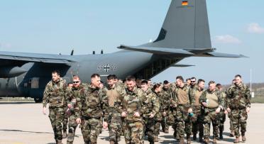 A group of soldiers debark from a military transport aircraft.