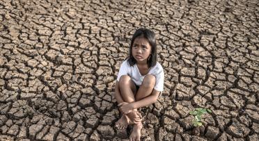Drought, girl sitting down on arid land