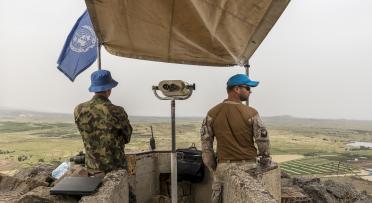 2 UN peacekeepers on a balcony looking at the horizon