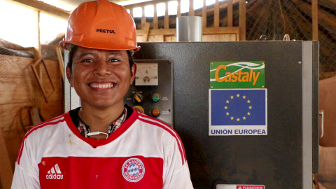 Young man smiles at the machinery donated by the EU for wood processing.
