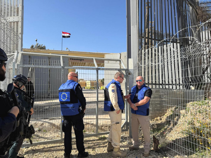 Exterior, uniformed people at the border crossing. 