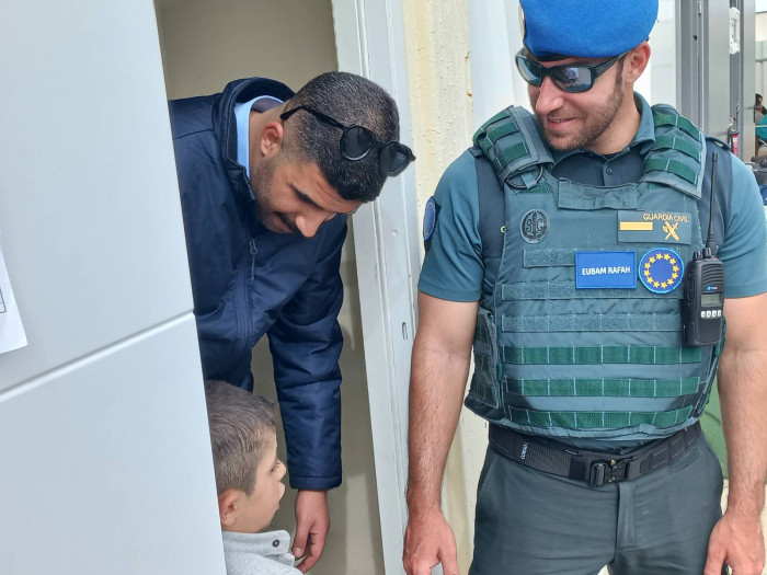 Two officers smiling with a young child. 