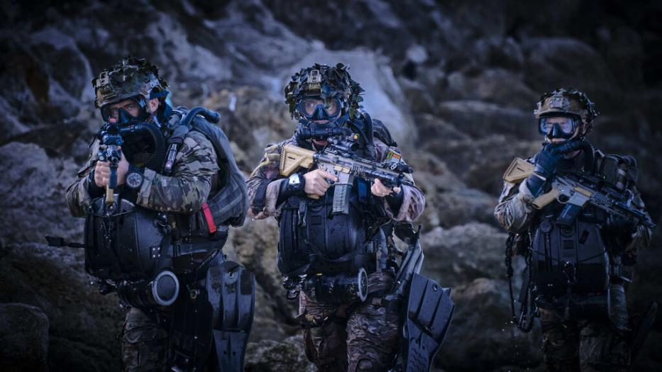 Three combat divers on a mission with full equipment and rifles.