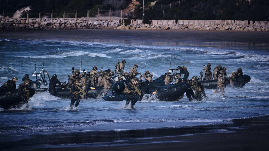 Dozens of combat personnel storm ashore during amphibous landing. 