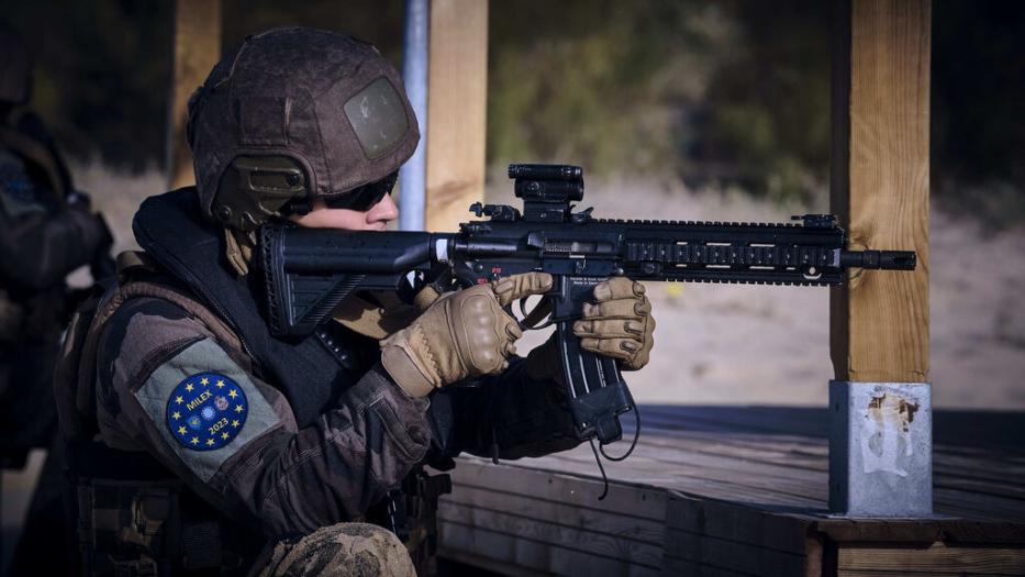 Soldier with Milex patch aiming combat rifle down range.