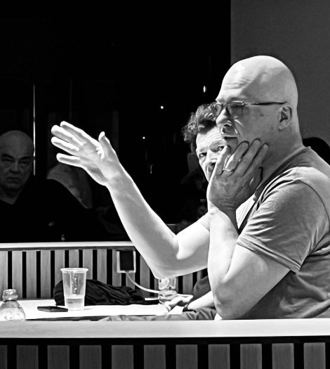 Monochrome colour of middle aged man in tshirt talking to students. 