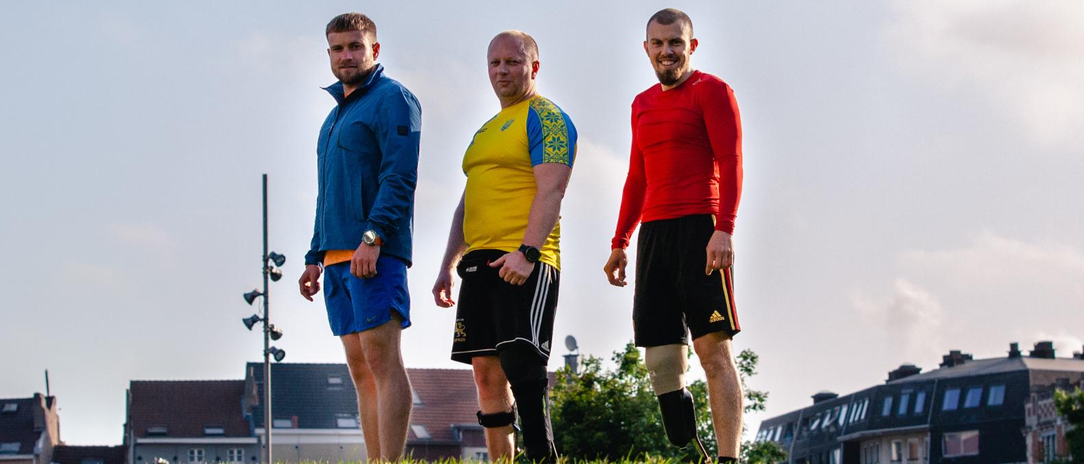 Three Ukraininan athlete war veterans pose outside in a park.