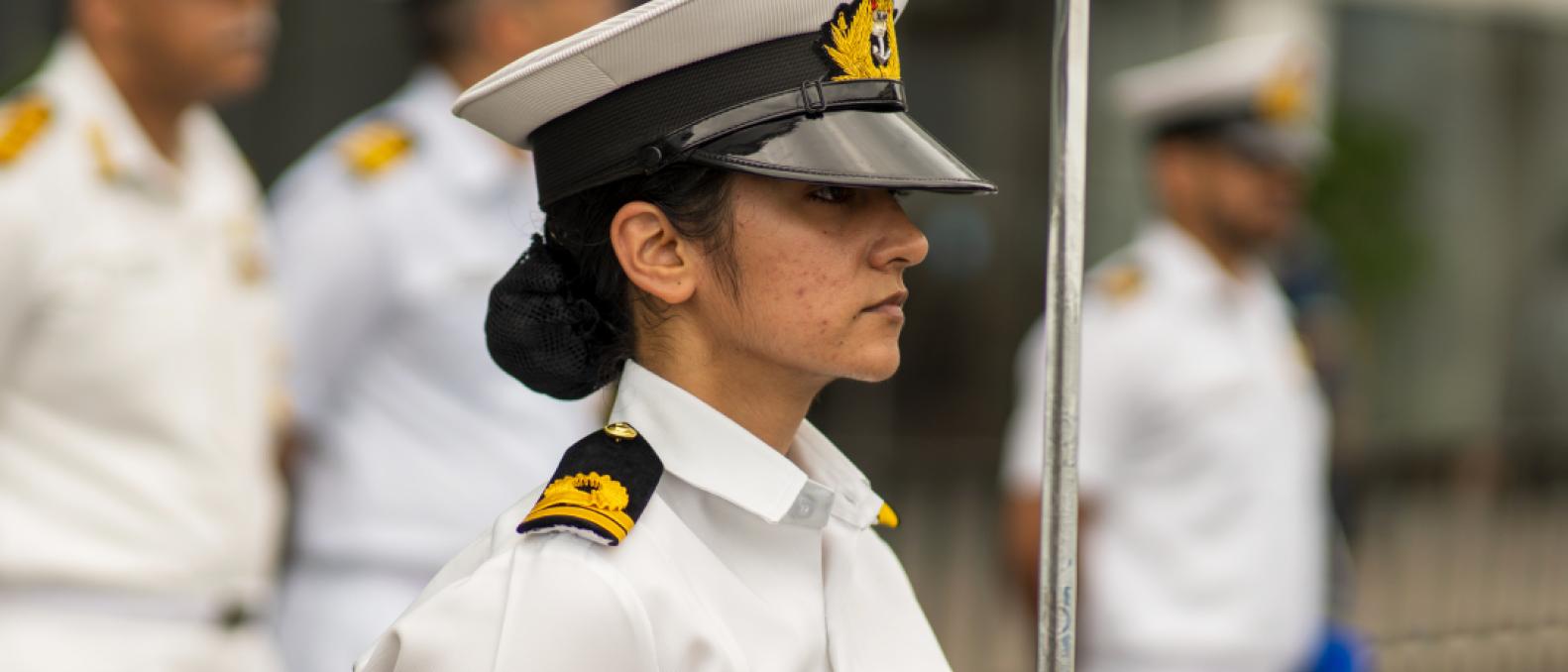 Young naval officer holding a sword in a parade on deck. 