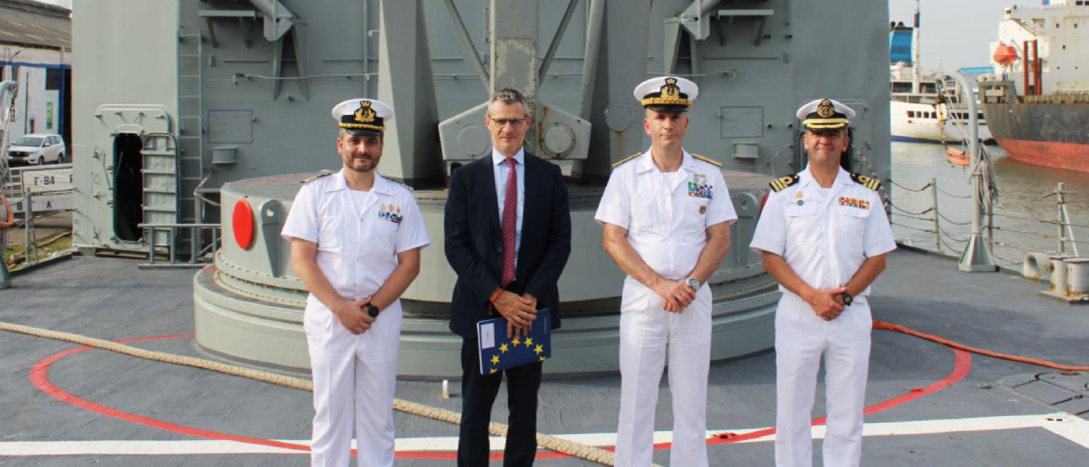 Four senior commanders and officials pose on deck of a naval ship. 