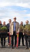 Picture of a large group of people, some holding small tree plants
