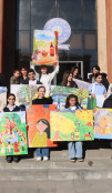 Young artists holding their artworks for EUMA's photo exhibition "What Equality Looks Like"