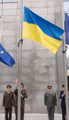 Flag raising ceremony outside with Ukrainian flag and EU flags. 
