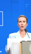 Kaja Kallas stands against a blue EU background. 