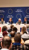 People at a press conference with EU branding in background