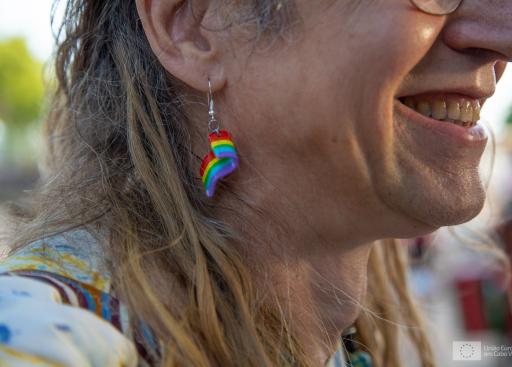 Picture of lady wearing an earring with a rainbow flag