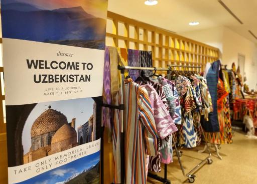 Banner that says 'Welcome to Uzbekistan' with rack of clothes behind