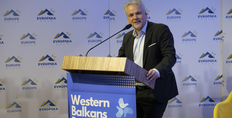 Ambassador Sattler standing behind lectern and speaking