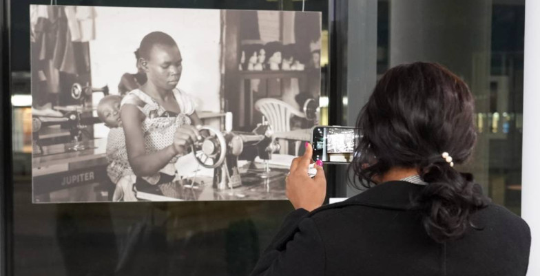 Behind the scenes photo of a woman taking a snapshot of an art exhibition. 