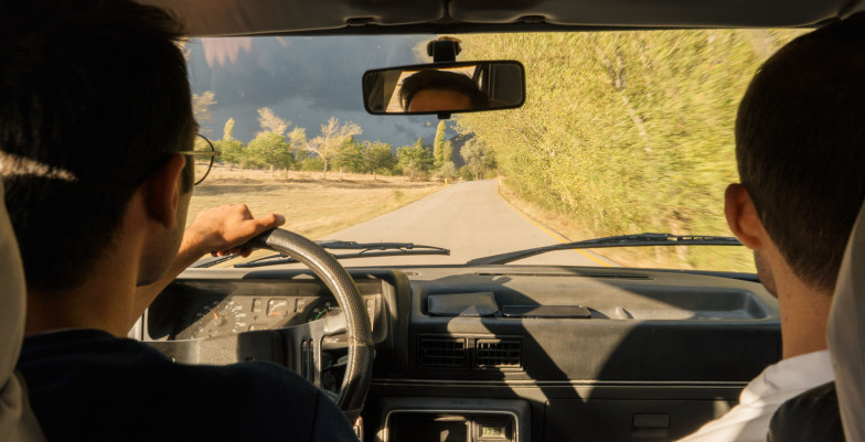 Two adults driving through scenic countryside.