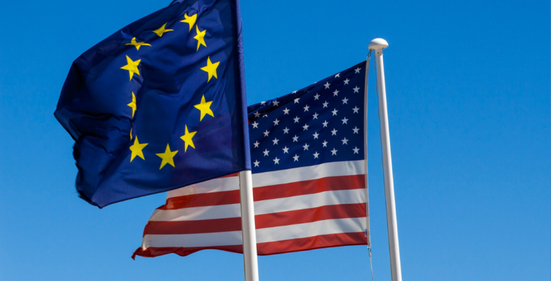 EU and US Flags flying in a clear blue sky