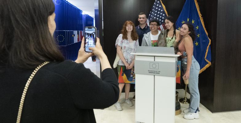 A person takes a picture of a group of friends behind a podium at EU Open House