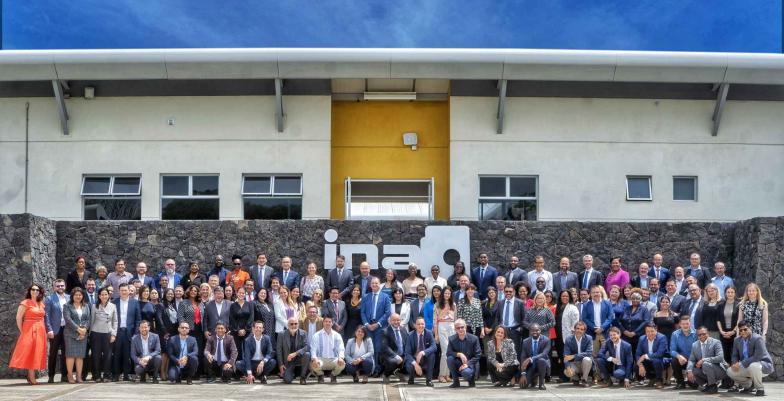 Group photo of around 100 delegates taken outside. 