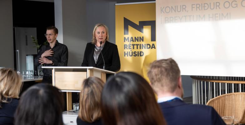 woman speaking at a podium in front of guests. A sign language interpretor to the left. 