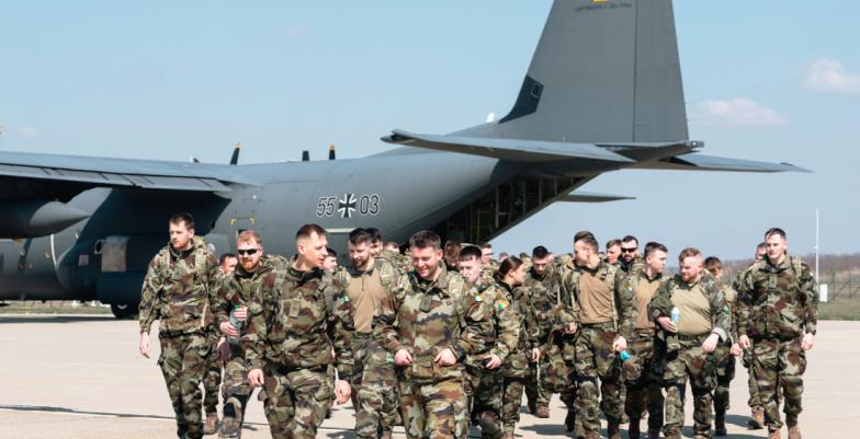 A group of soldiers debark from a military transport aircraft.