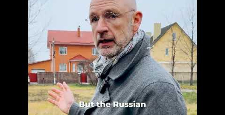 Thumbnail of man talking in front of ordinary houses. 