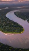 Imagem durante o pôr do sol de um rio sinuoso cruzando a Floresta Amazônica.