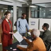 Voting room, woman receiving ballot paper