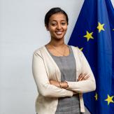 A woman posing to the camera with a EU flag next to her