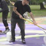 Young adult man with short brown hair painting a football field.