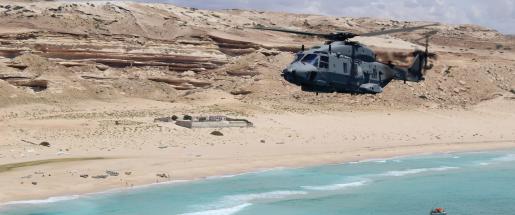 a helicopter approaching a deserted beach