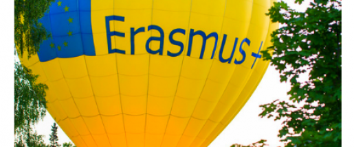 Yellow Erasmus Plus hot air balloon ready to launch in a park with people surrounding the balloon.
