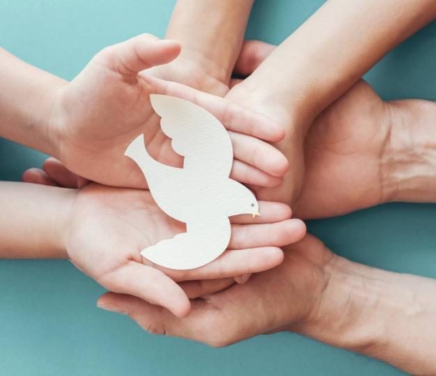 Small child’s hands holding a paper dove