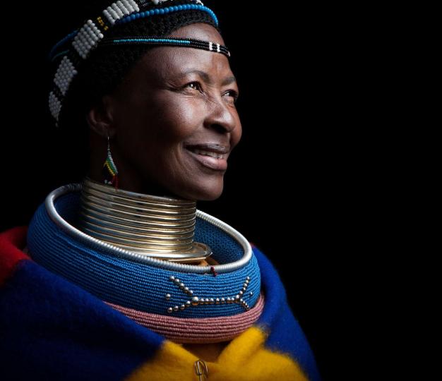 Mature African lady in tribal ceremonial costume smiling. 