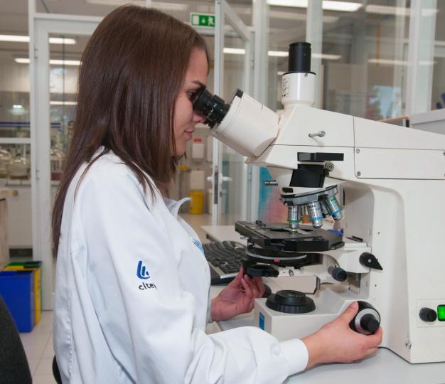 An employee of the CITEVE (Technological Center of the Textile and Clothing Industries of Portugal), looking into a microscope 